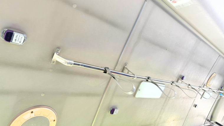 小さな路線バスの天井に取り付けられた吊り革と下車ボタン。シンプルな車内設備の様子。