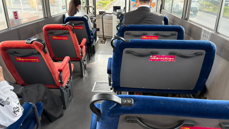 小さな路線バスの車内。すべての座席が前向きに配置され、落ち着いた雰囲気がある。